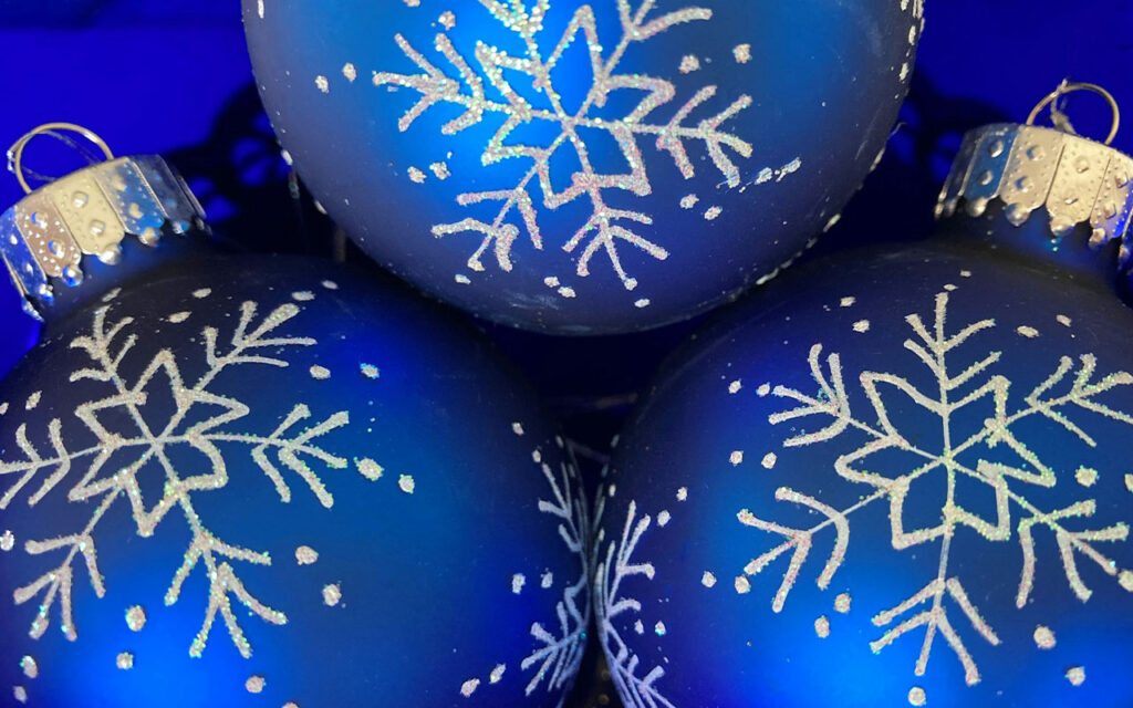three Christmas baubles with snowflake patterns applied